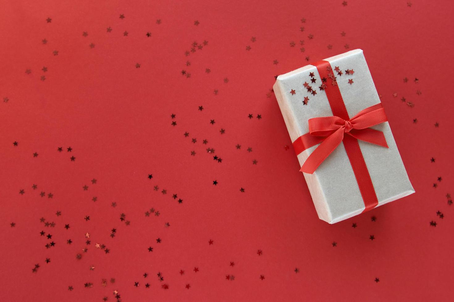 composição de natal. giftbox com fita vermelha e enfeites de confetes em fundo colorido de papel pastel. Natal, inverno, conceito de celebração do ano novo. lay lay, top view, copy space foto