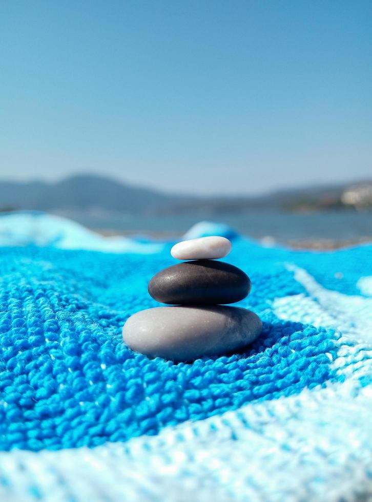 Pedras de seixo em toalha azul na praia de verão foto