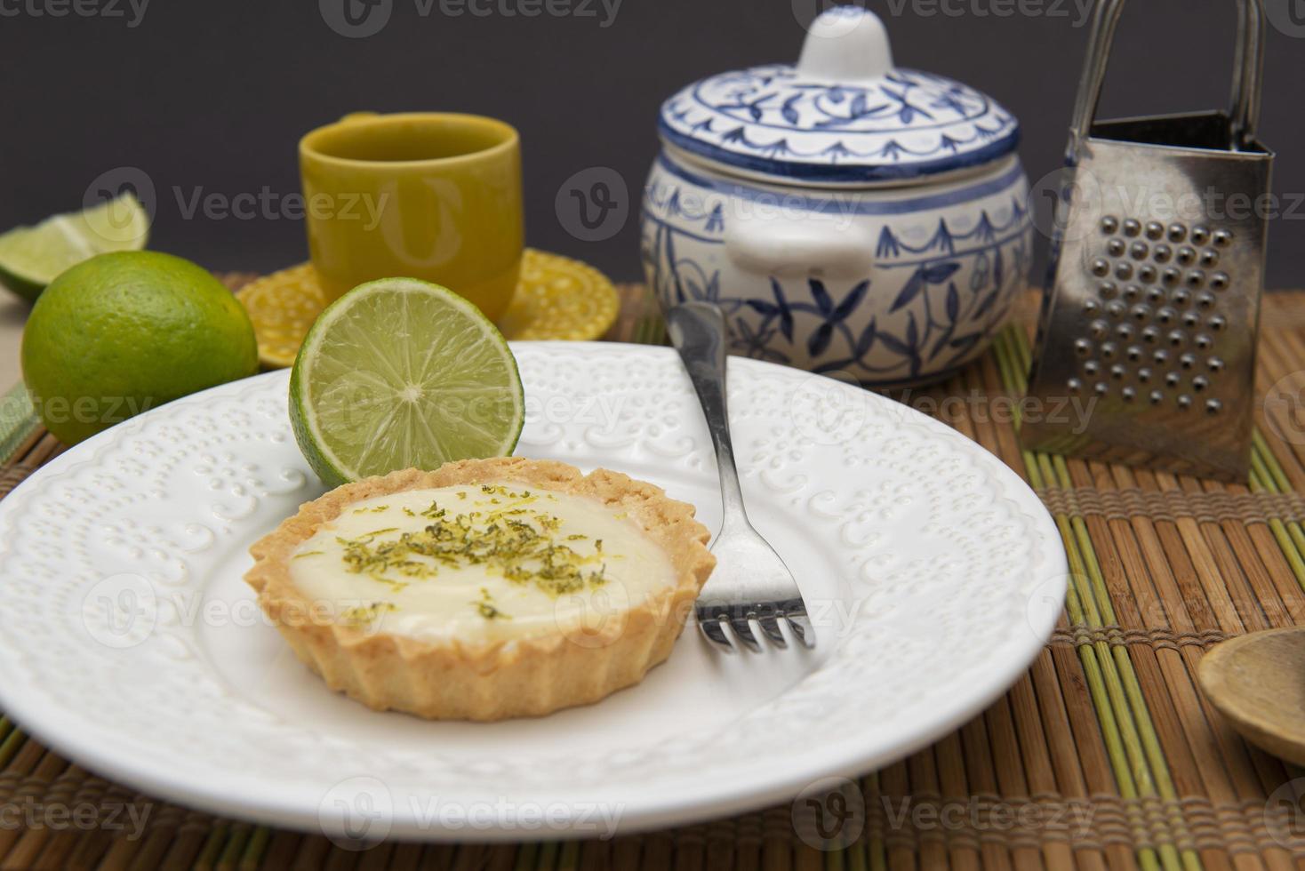 vista lateral da torta de limão no prato prato com rodelas de limão na mesa. foto