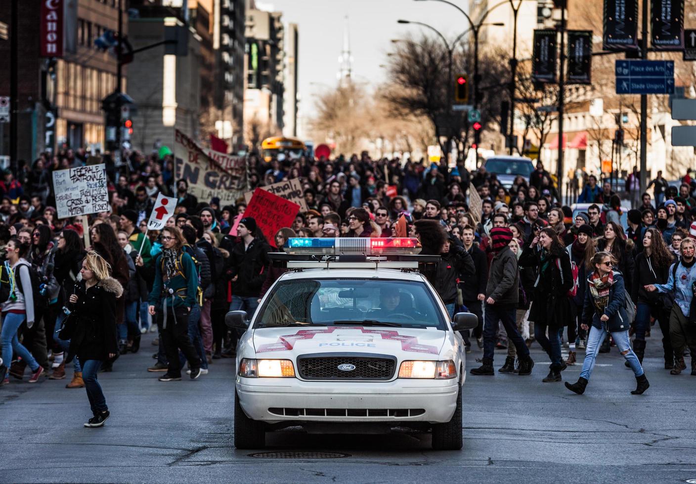 montreal, canadá, 2 de abril de 2015 - carro da polícia na frente dos manifestantes controlando o tráfego foto
