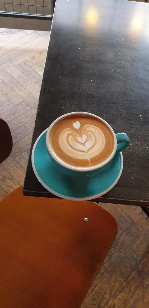 leite café com formato de coração em um copo azul sobre a mesa foto