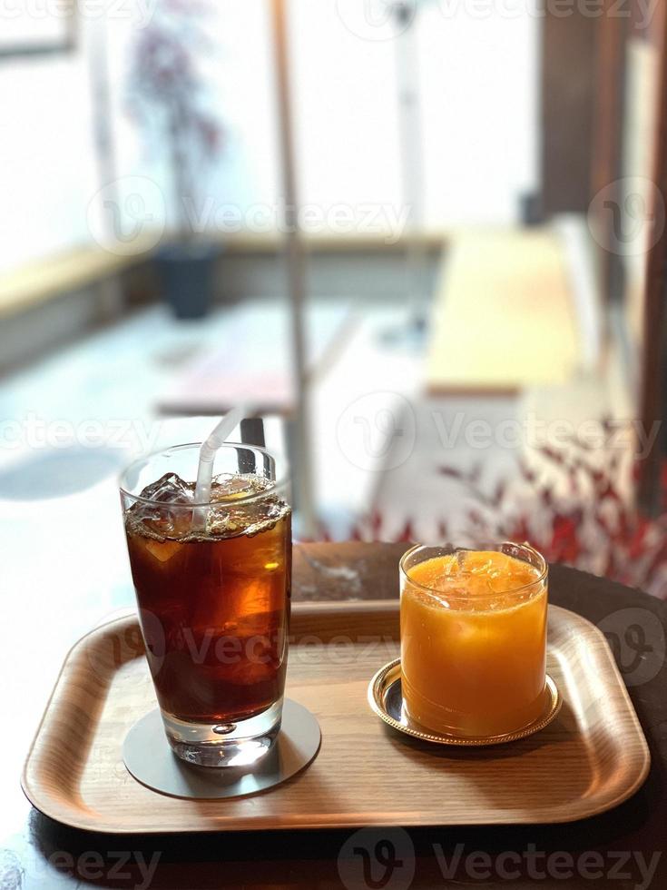 chá gelado em um copo e gelo de laranja em um copo em uma bandeja foto