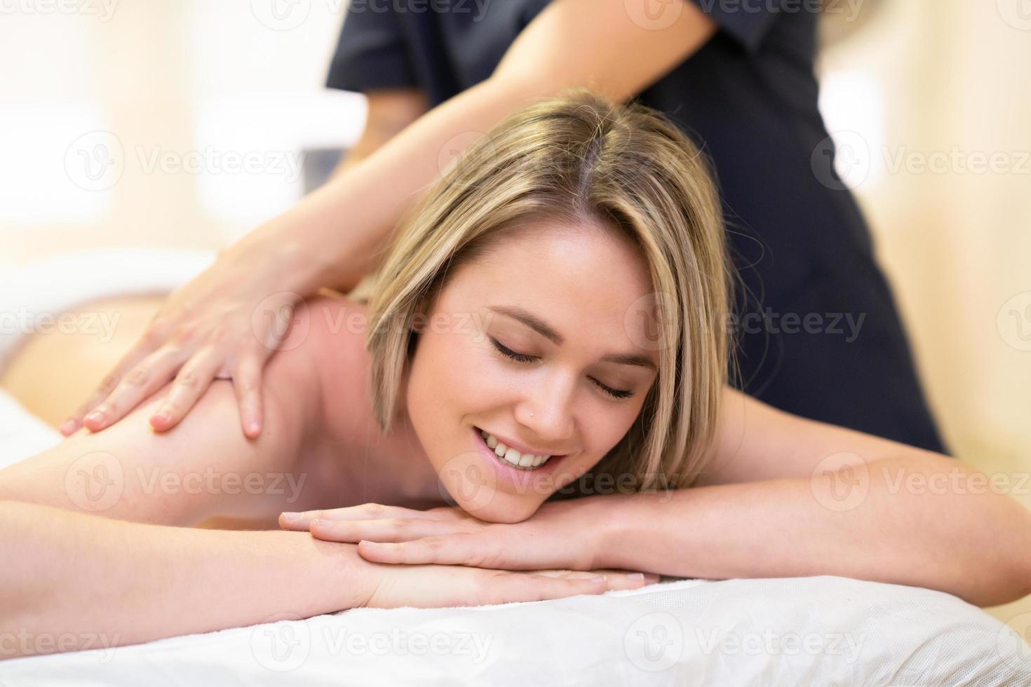 mulher deitada em uma maca, recebendo uma massagem nas costas. foto
