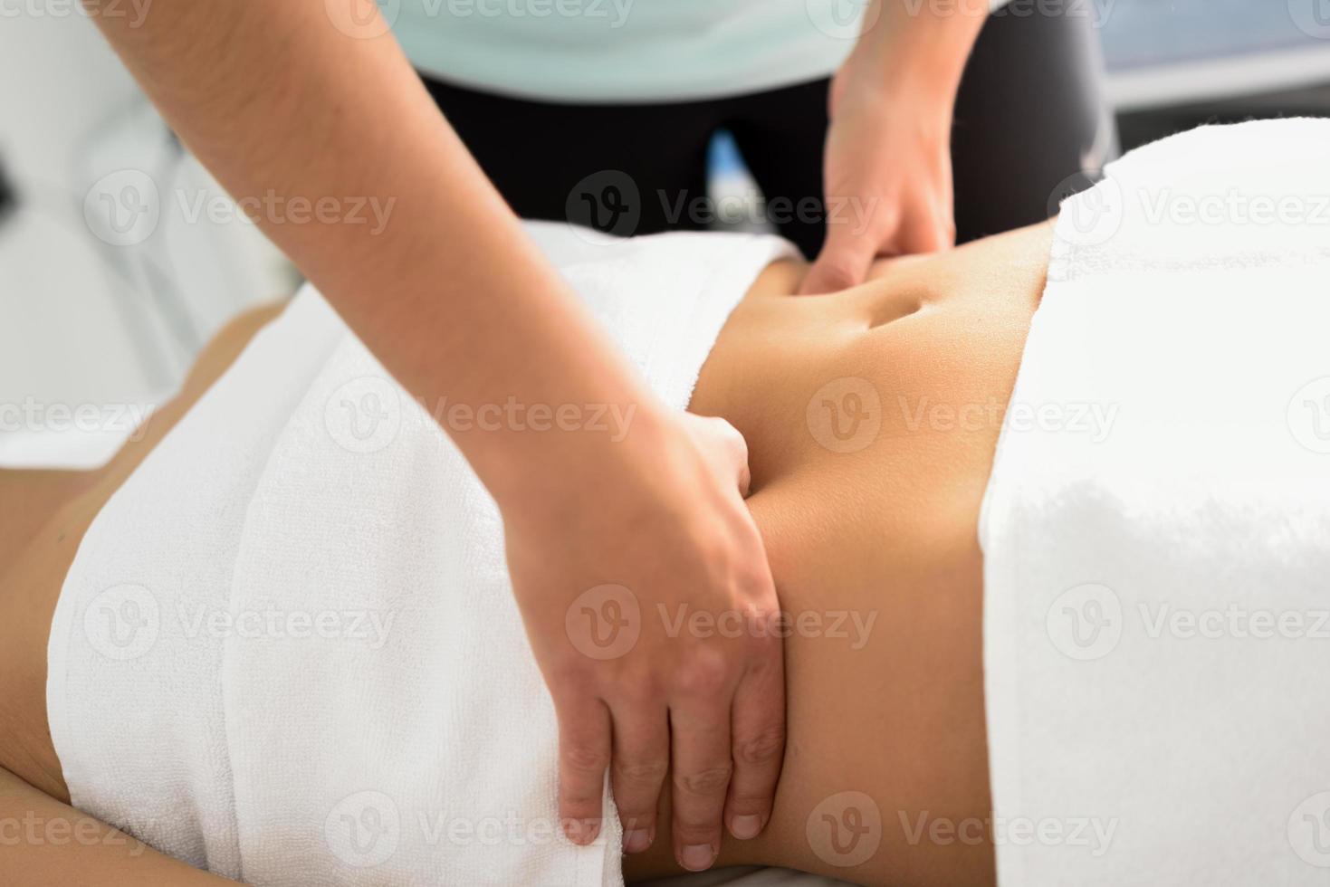 mãos massageando o abdômen feminino. terapeuta aplicando pressão na barriga. foto