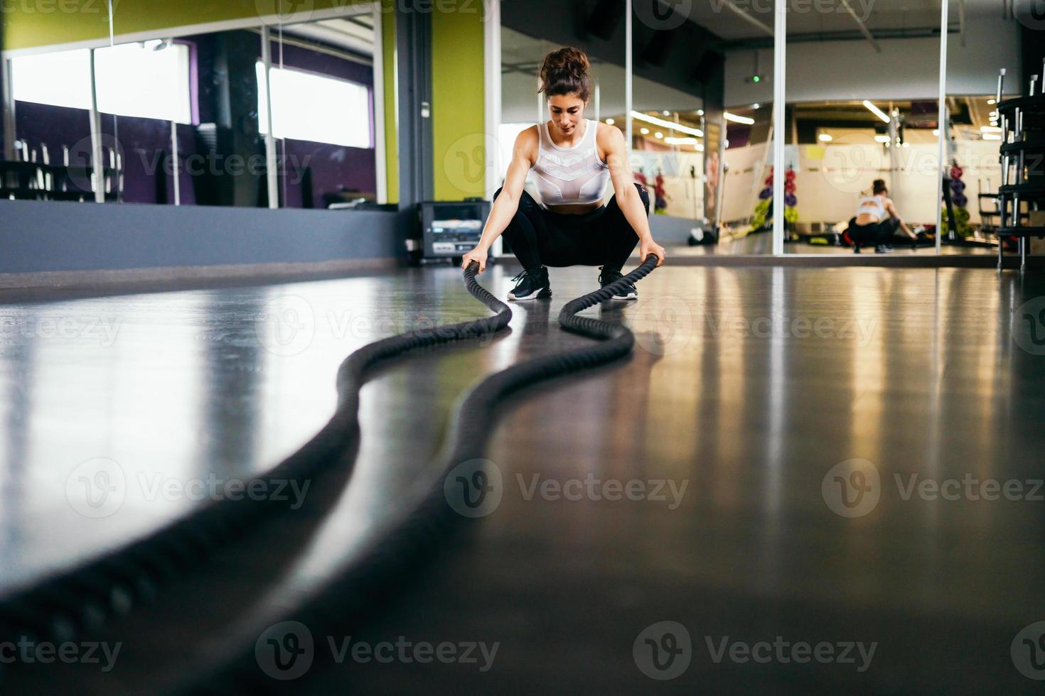 mulher jovem e atlética, usando cordas de treinamento em um ginásio. foto