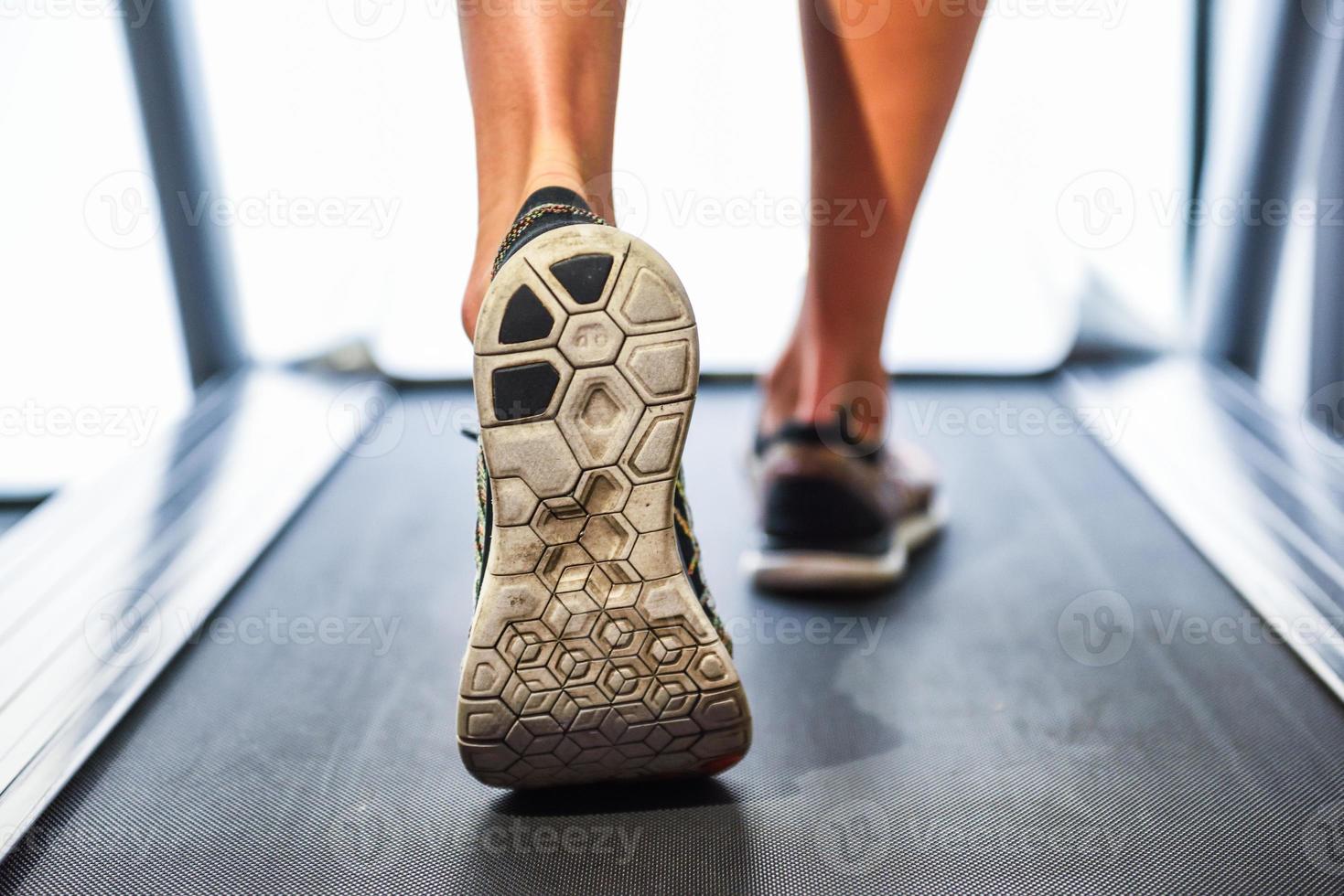 pés musculosos masculinos de tênis correndo na esteira na academia. foto