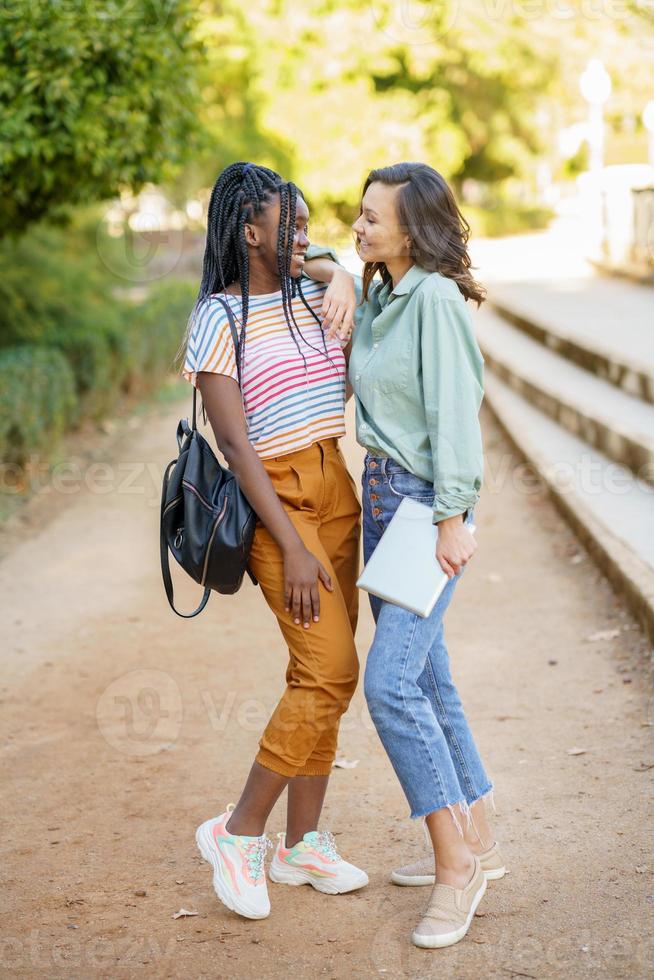 duas mulheres multiétnicas posando juntas com roupas casuais coloridas foto