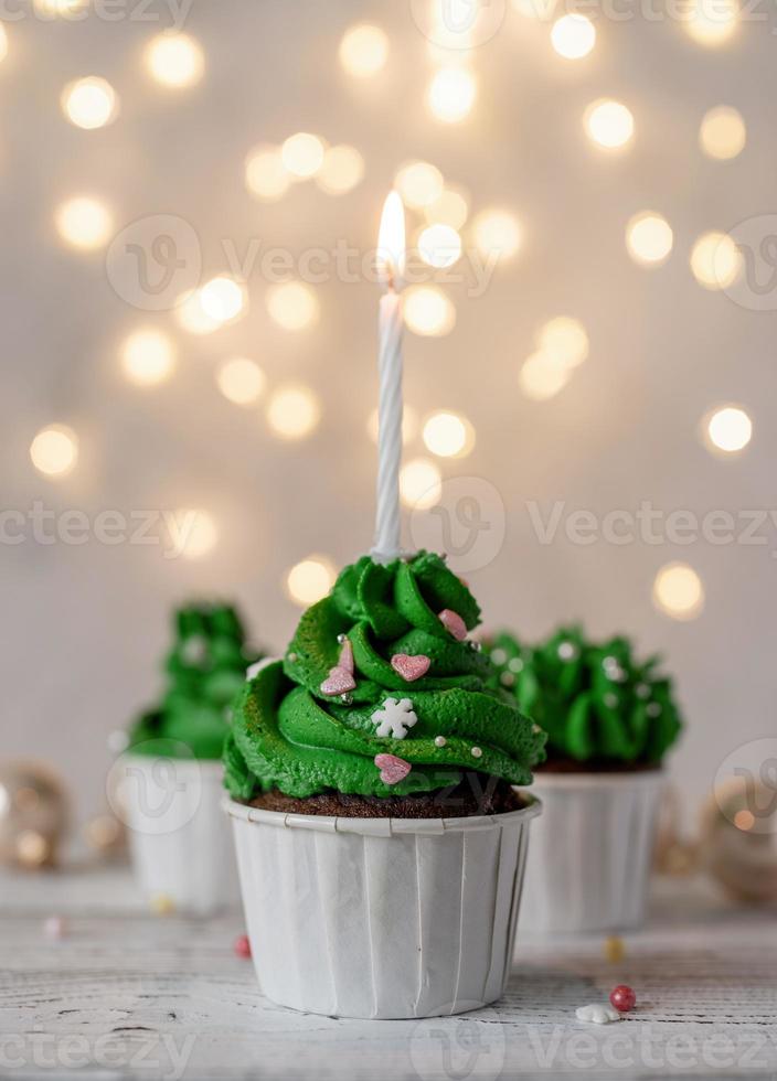 cupcakes em forma de árvore de natal, rodeados de decorações festivas e luzes no fundo foto