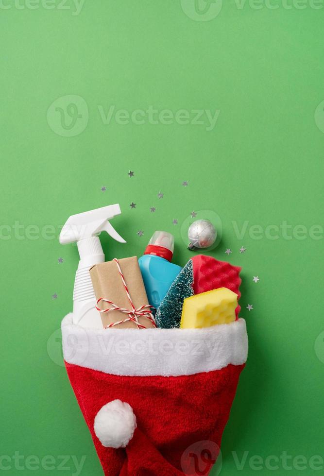 ferramentas de limpeza e decorações de Natal com chapéu de Papai Noel vista superior plana sobre fundo verde com espaço de cópia foto