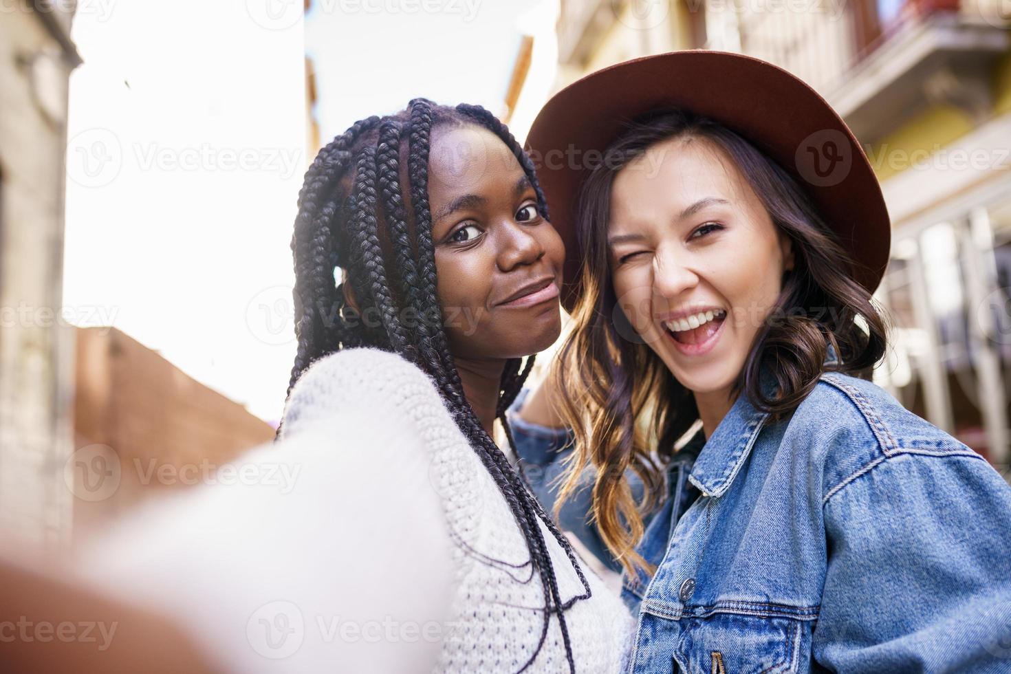 duas lindas mulheres multiétnicas fazendo selfie e fazendo caretas foto