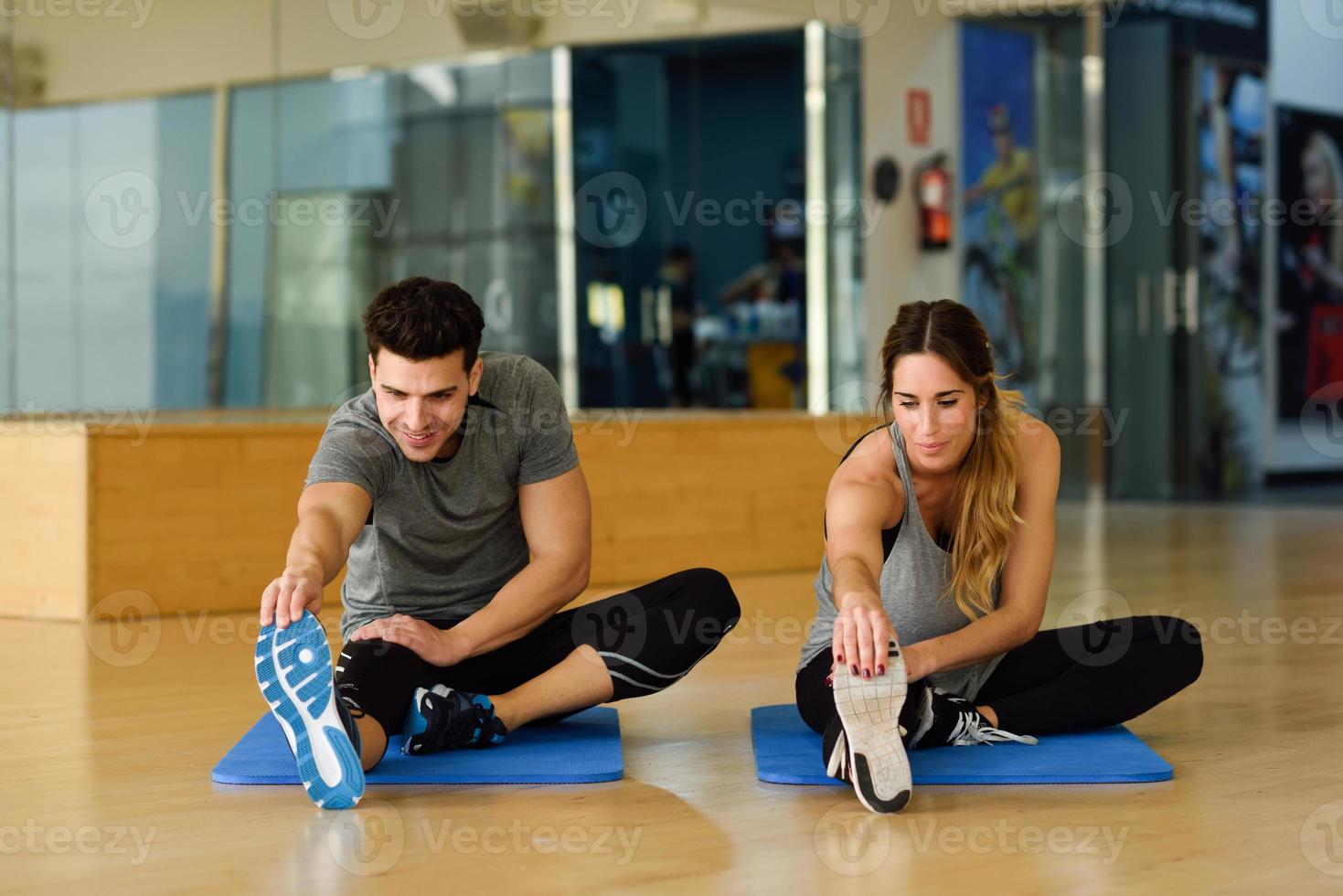 duas pessoas esticando as pernas na academia. foto