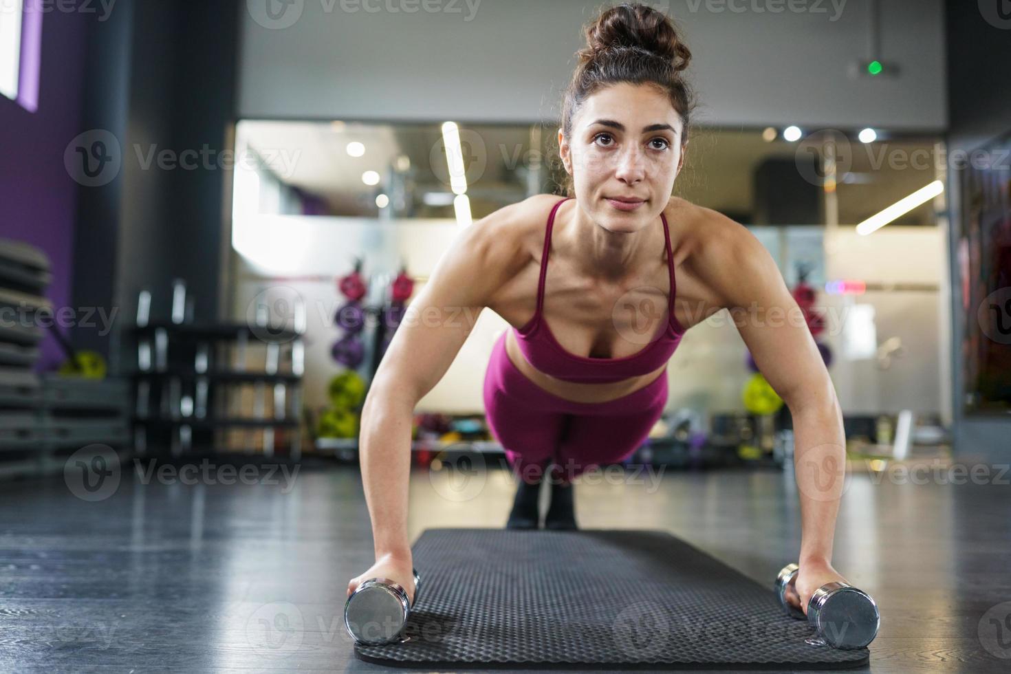 mulher fazendo exercícios de flexão com halteres em um treino de fitness foto
