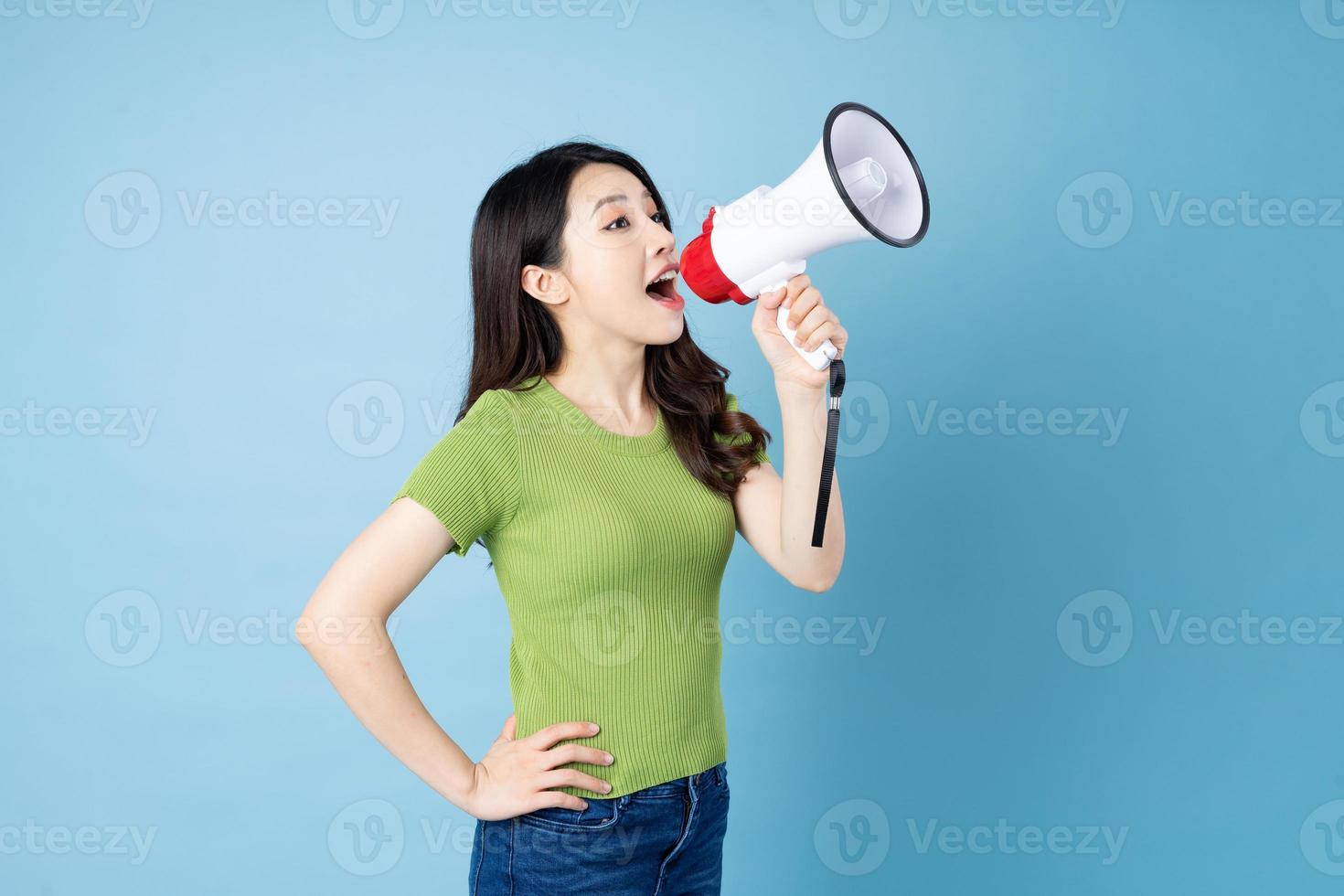 retrato de menina asiática segurando um alto-falante, isolado em um fundo azul foto