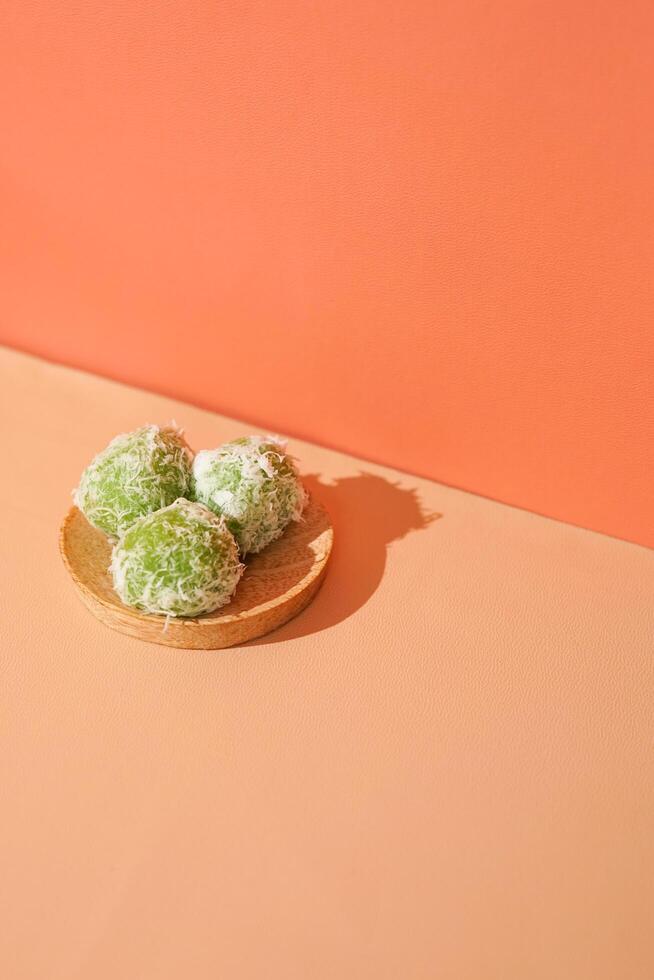 klepon, um dos alimentos tradicionais da Indonésia. o bolinho de arroz em verde polvilhado com coco ralado. uma foto de comida local para apresentações ou promoções com espaço de cópia.