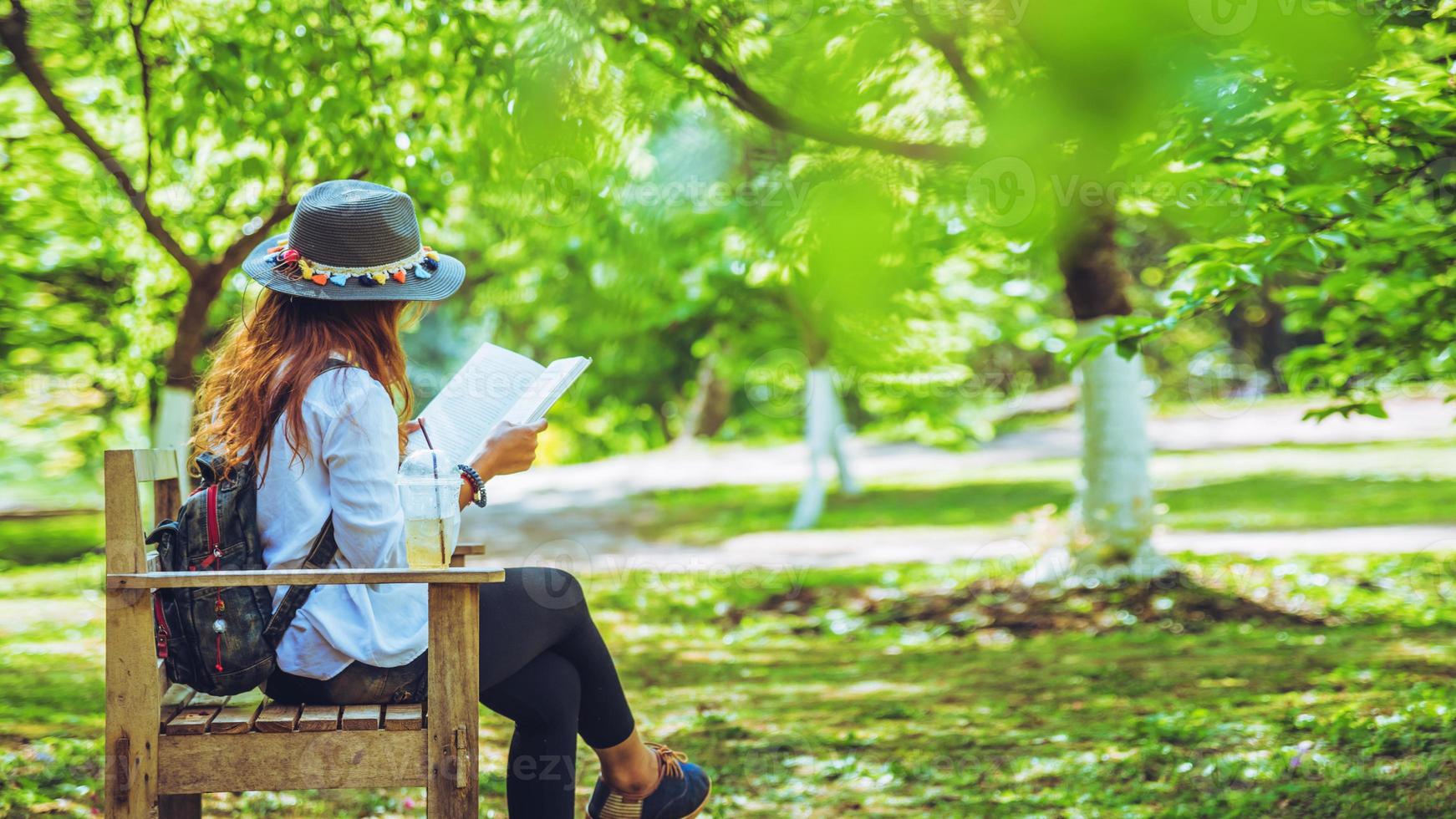 mulher viajante da liberdade sentada e lendo no parque e apreciando uma bela natureza. espaço para texto. foto