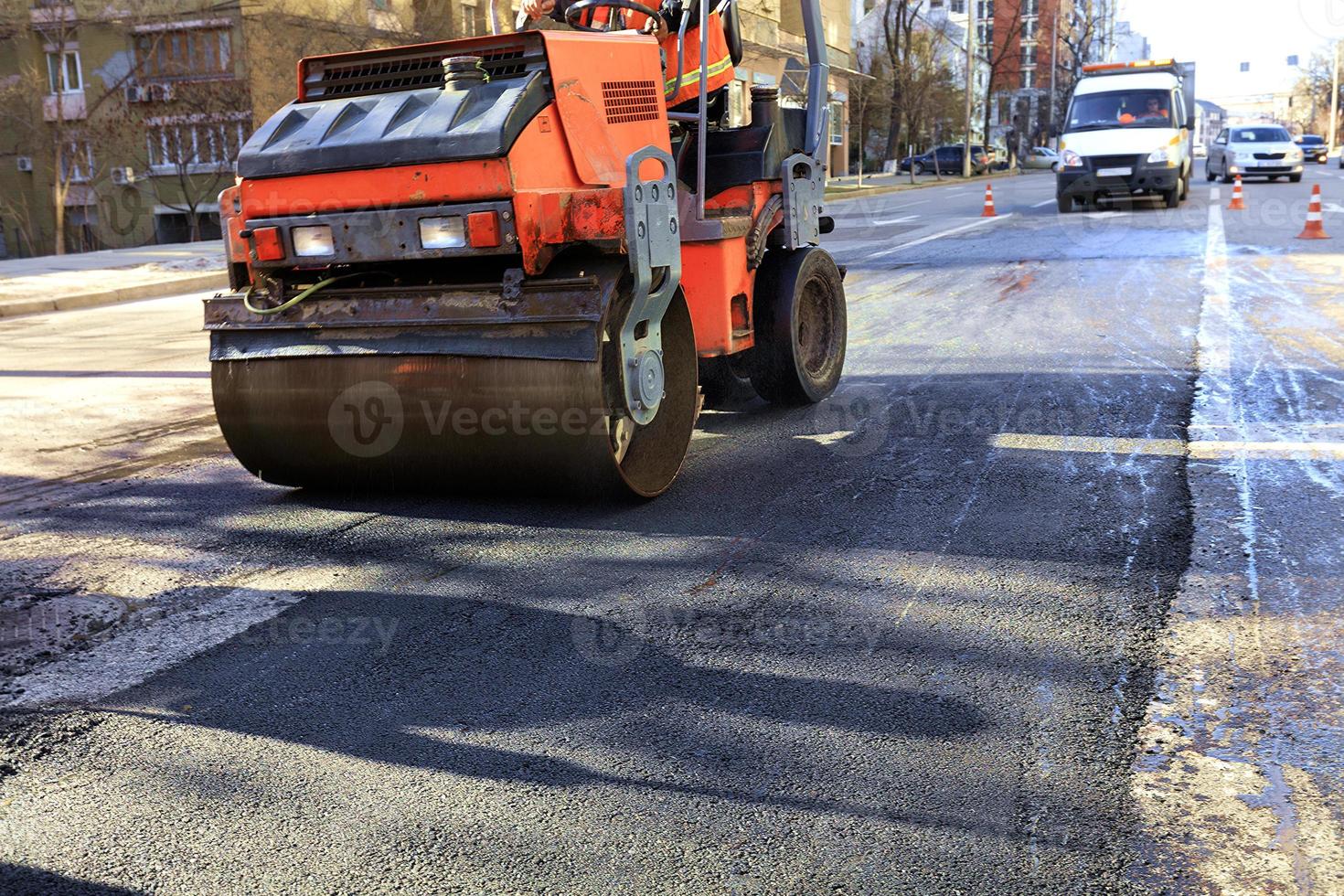 um rolo compactador vibratório pesado compacta asfalto na estrada a ser reparada. foto