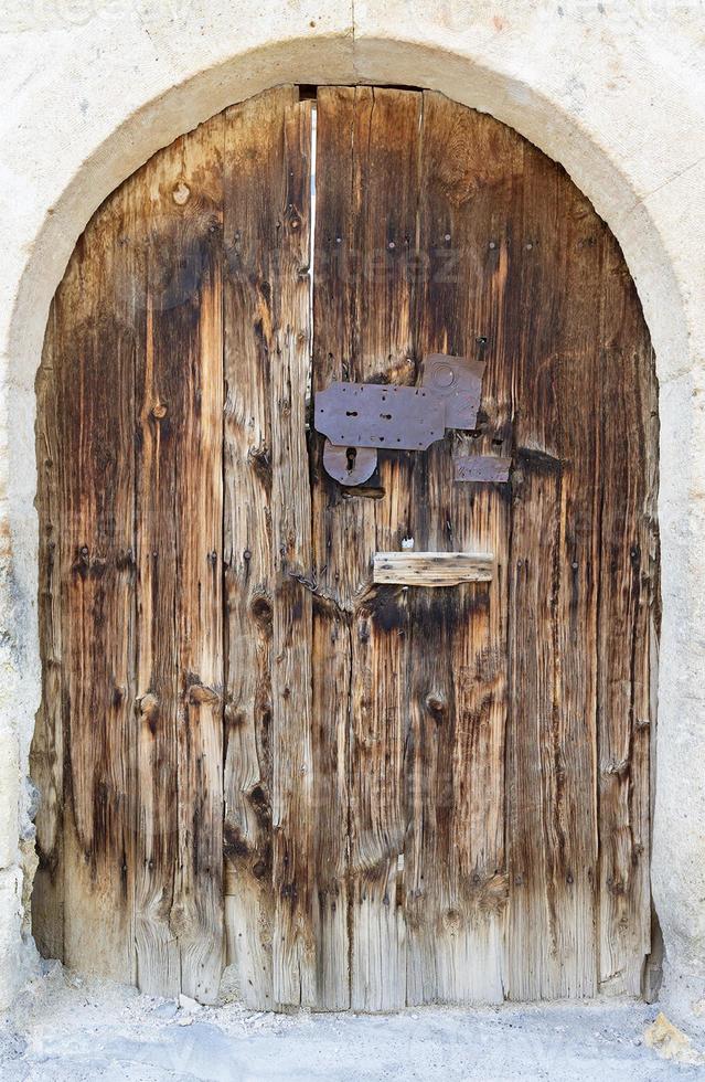 portas de madeira antigas em arco com uma fechadura de metal no meio foto