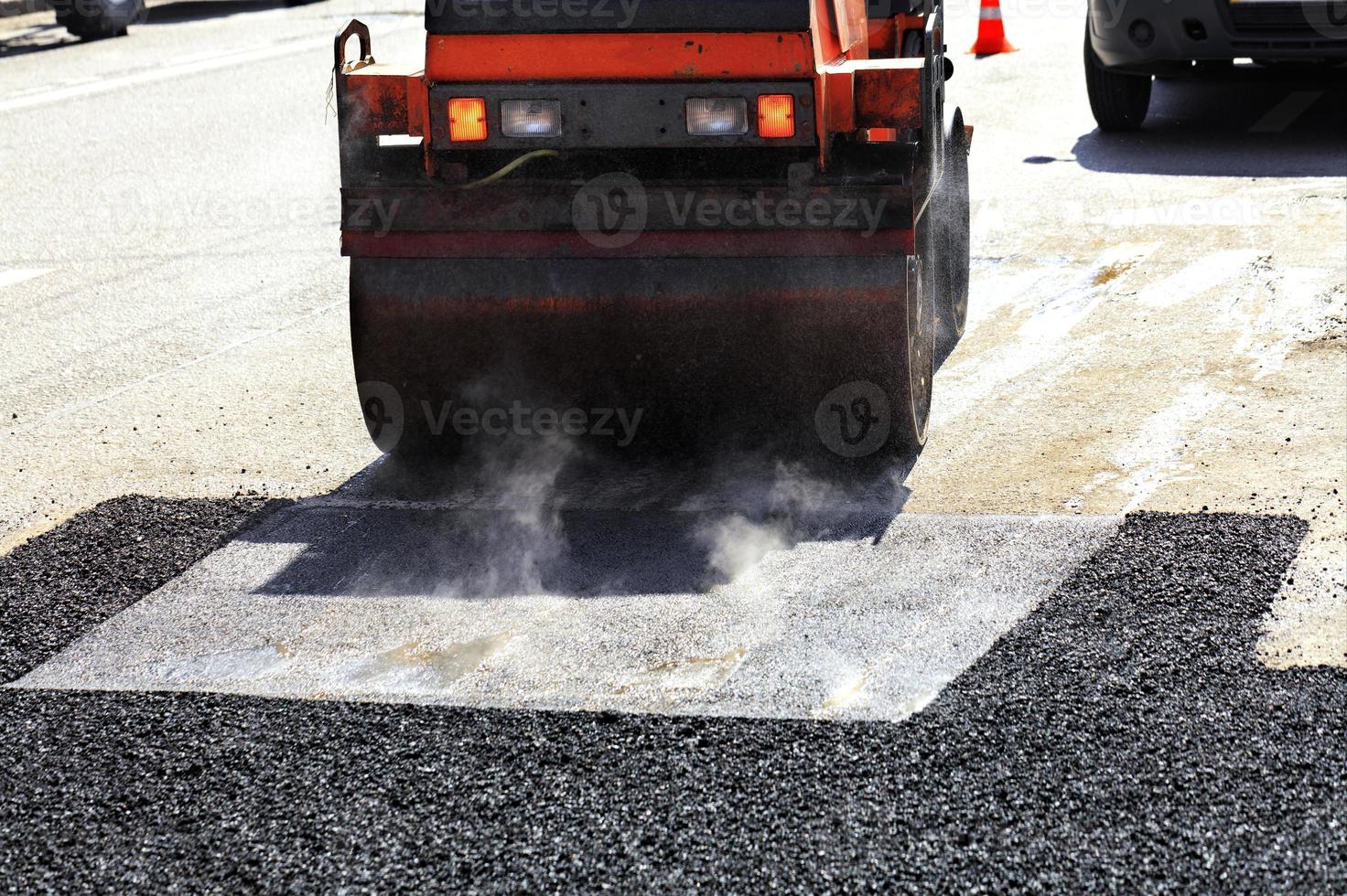 um rolo compactador vibratório pesado compacta asfalto no trecho reparado da estrada. foto