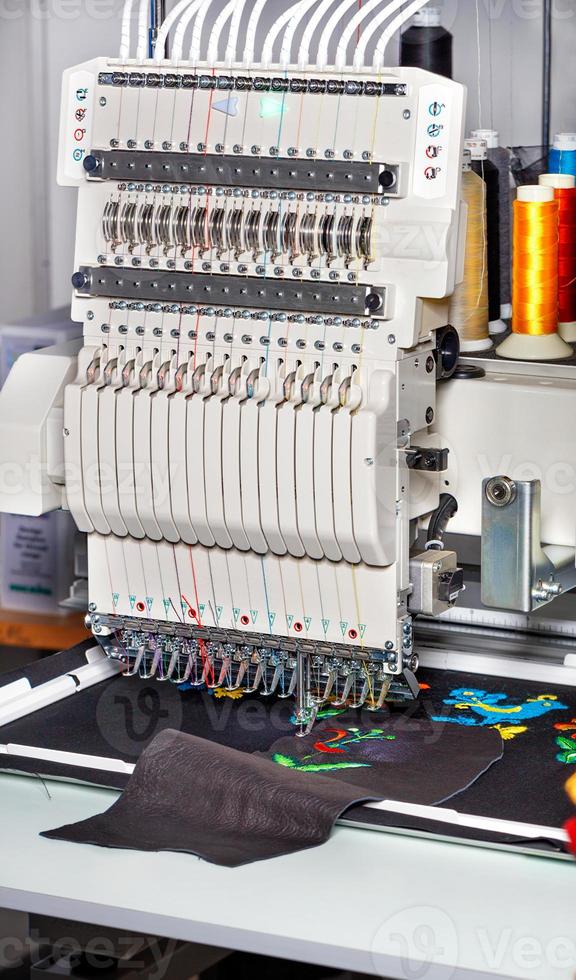 máquina de bordar industrial com fios multicoloridos, close-up, imagem vertical. foto