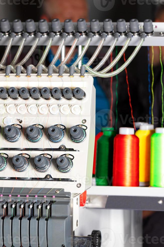 fragmento de uma máquina de bordado industrial com fios multicoloridos em um borrão, close-up. foto