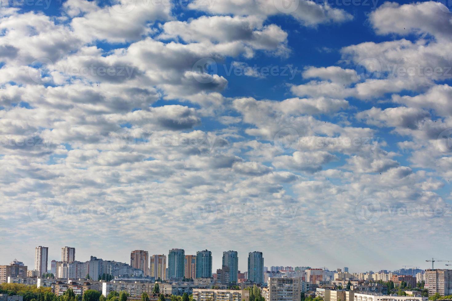 pequenas nuvens cinza-branco obscurecem gradualmente o céu azul acima da cidade. foto