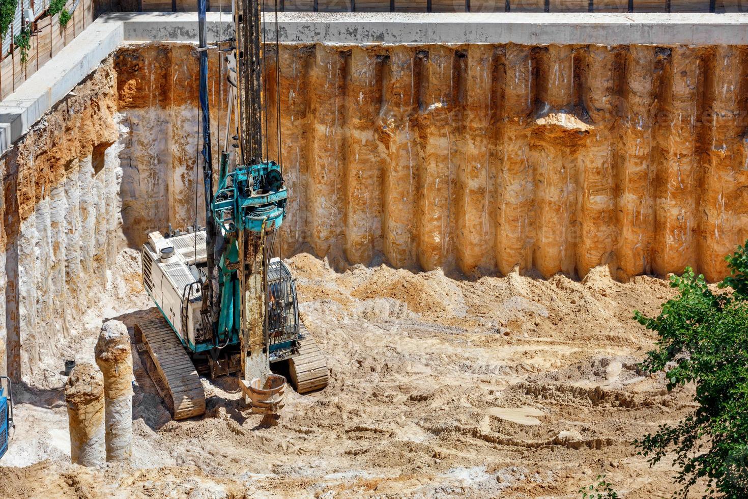 uma escavadeira pesada em conjunto com uma plataforma de perfuração trabalha para fortalecer a base do futuro edifício alto. foto