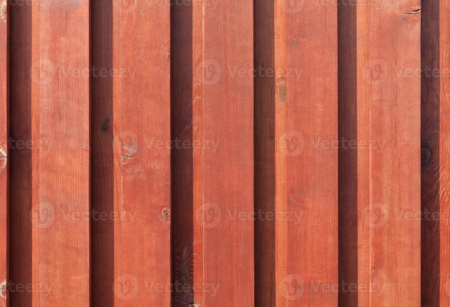 nova cerca de madeira marrom-vermelha nos raios de sol. foto