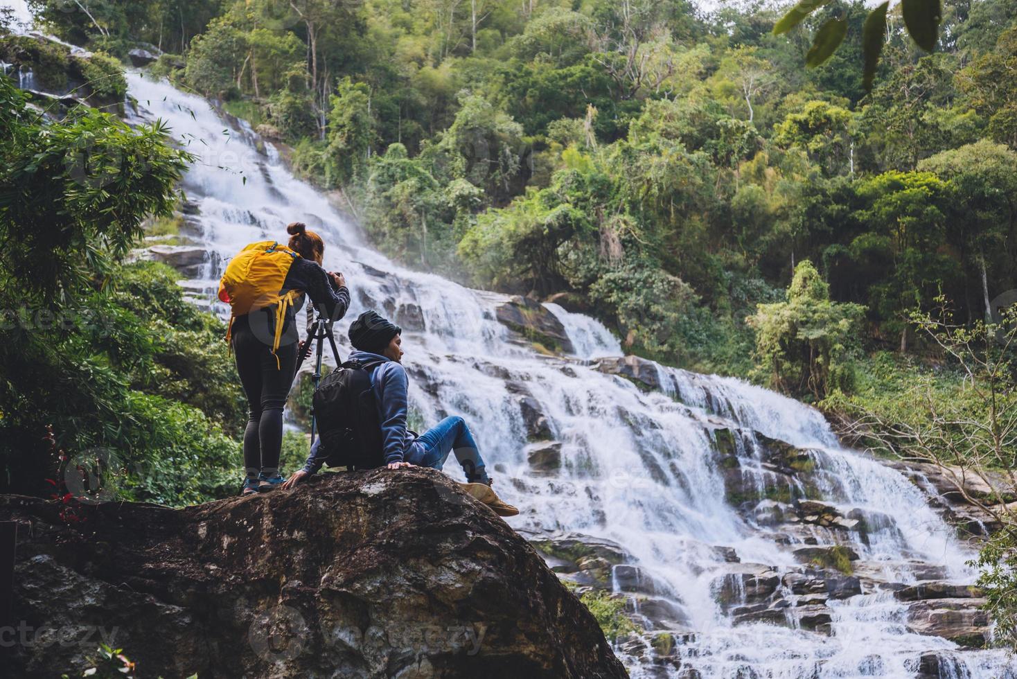 casal asiático viaja pela natureza. viajar relaxar. stand paisagens naturais touch stand para ver belas cachoeiras mae ya em chiangmai na tailândia foto