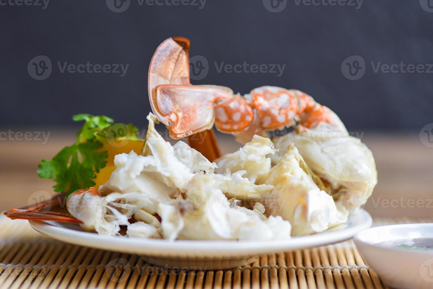carne de caranguejo - garras e patas de caranguejo cozidas em um prato branco e molho de frutos do mar na mesa, caranguejo nadador azul foto