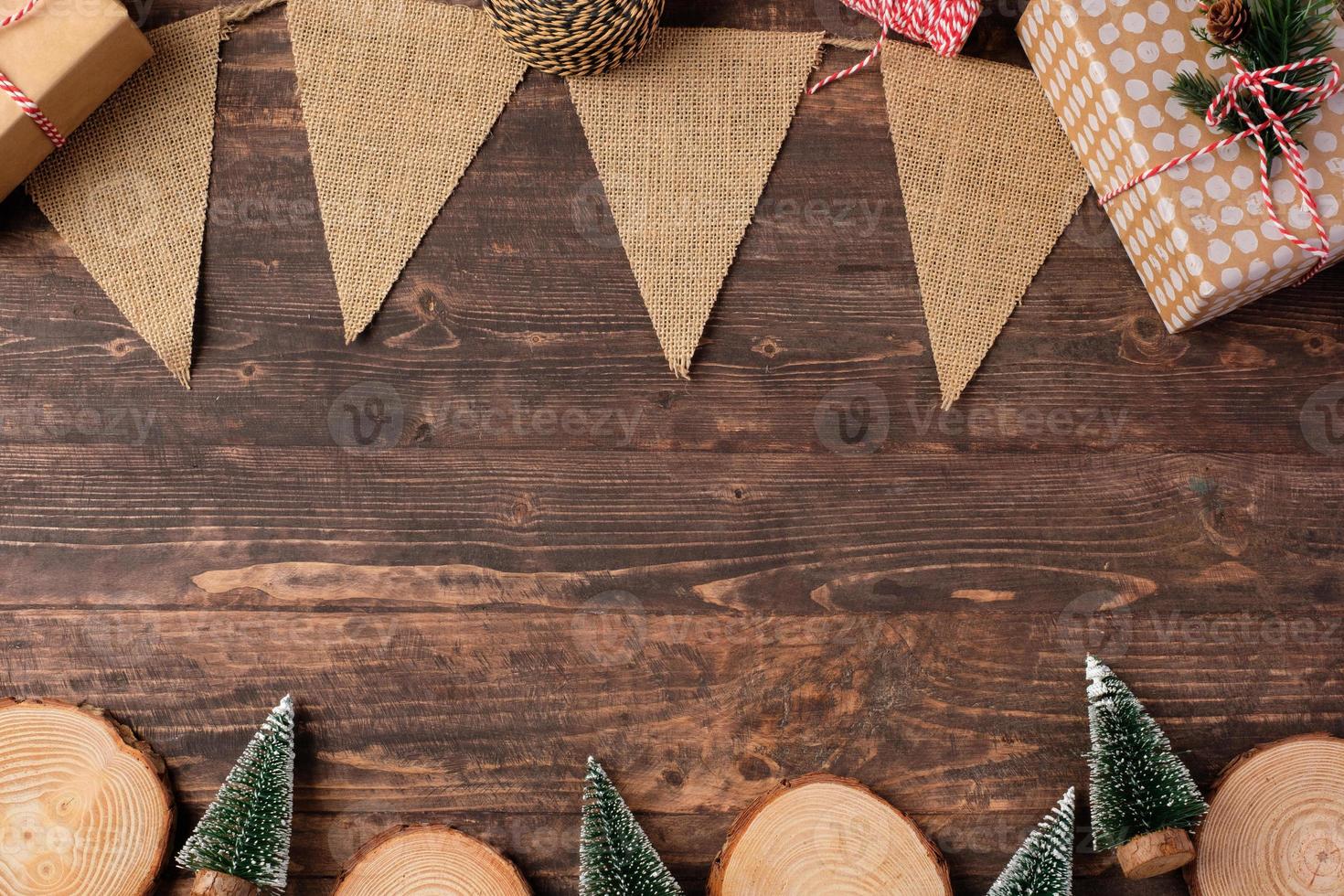 placa de madeira de natal e bandeira kraft e árvore de natal na mesa de madeira marrom foto