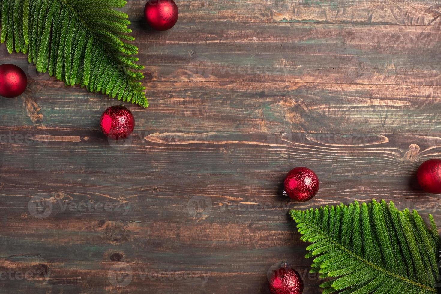 folha de pinheiro de natal com decoração bugiganga vermelha na mesa de madeira foto