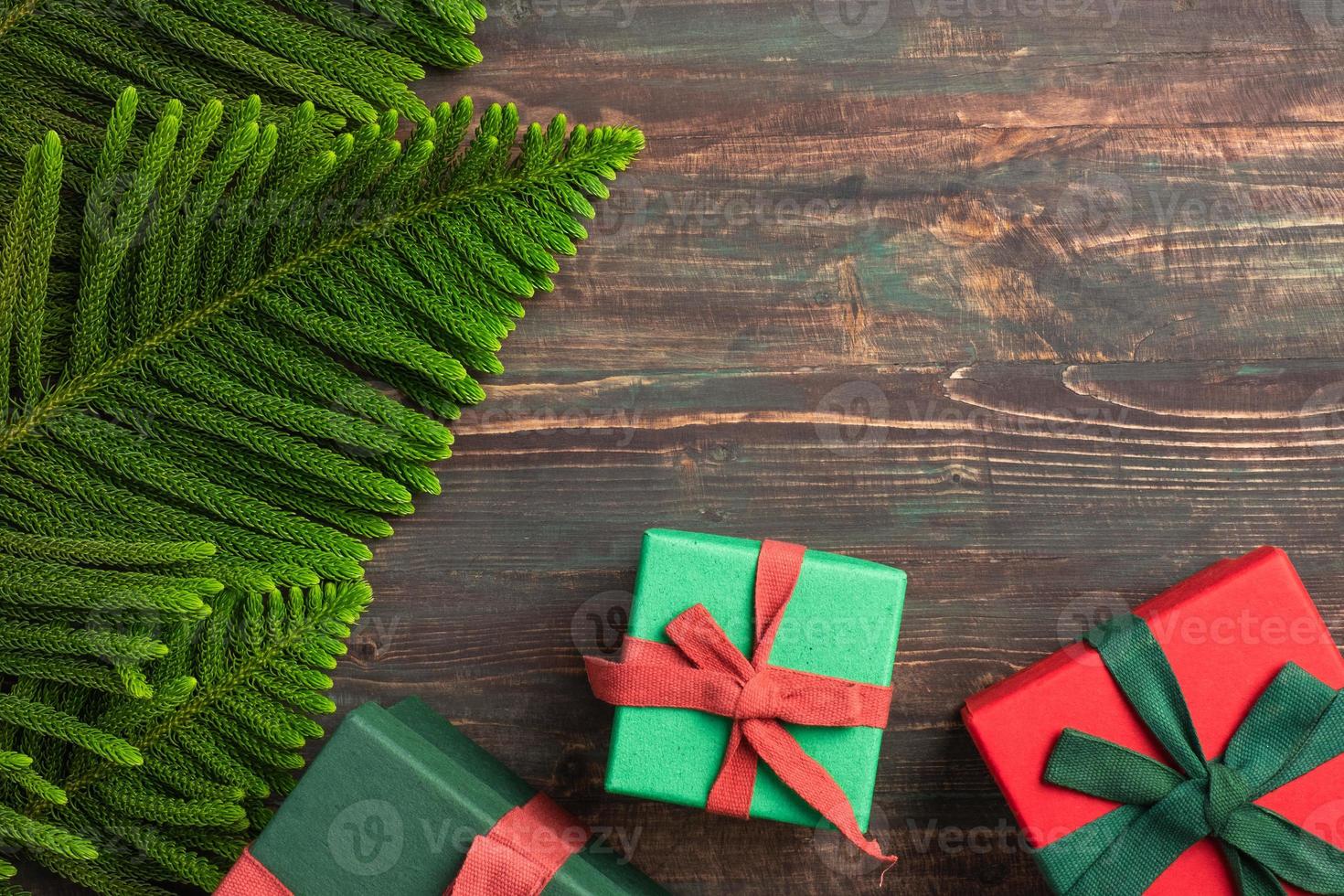 caixa de presente colorida de Natal com folha de pinheiro e enfeite de decoração na mesa de madeira foto