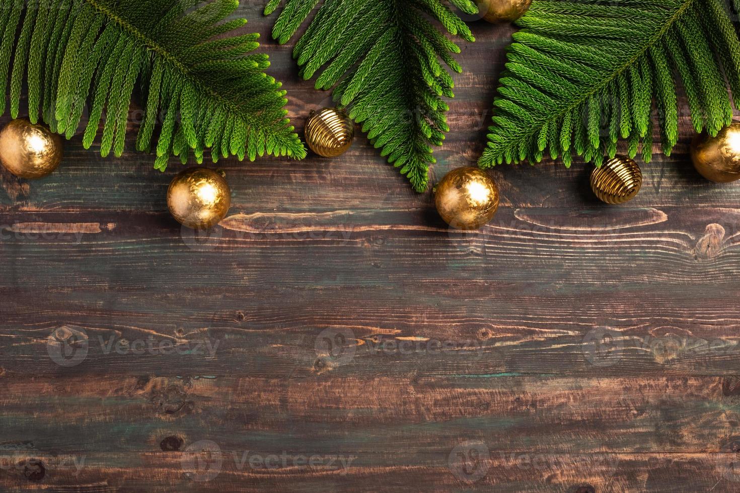 folha de pinheiro de natal com decoração de bugiganga dourada na mesa de madeira foto
