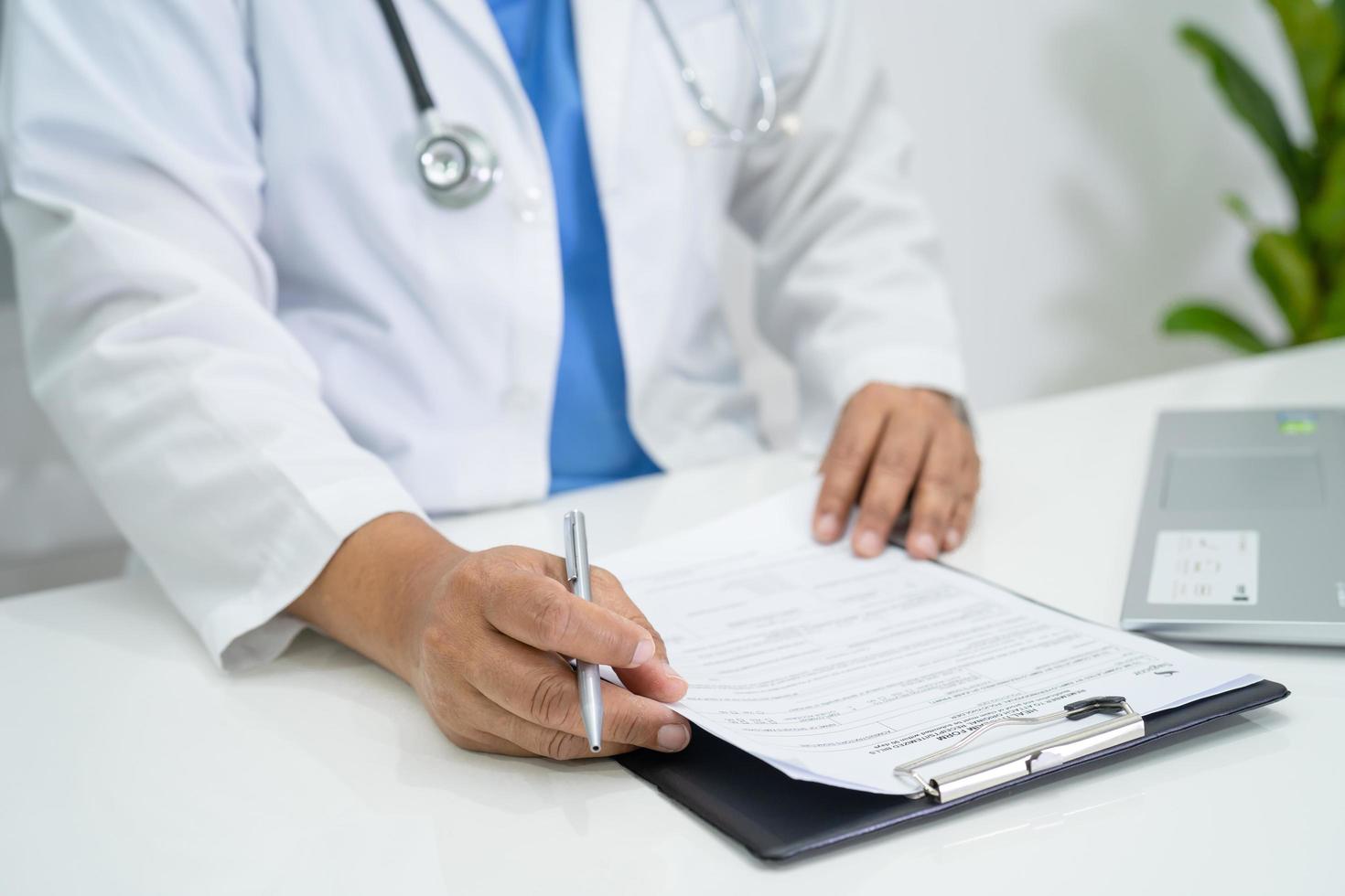 médico escrever nota médica de saúde na área de transferência com o laptop no hospital. foto