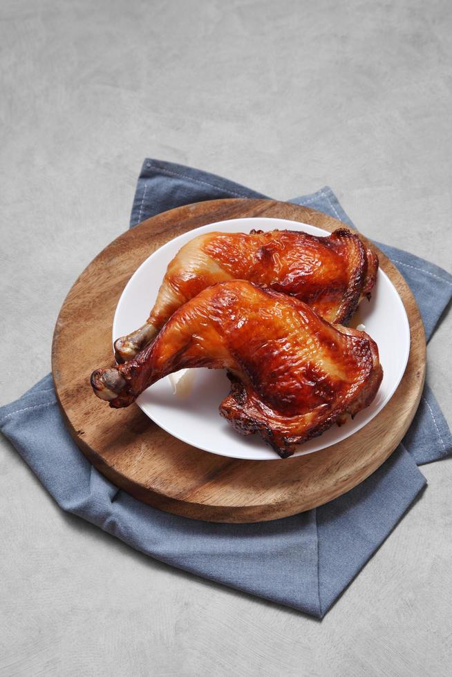 Coxa de frango grelhado em travessa de cerâmica na bandeja de madeira foto