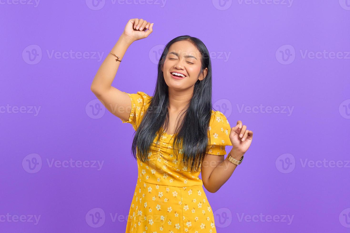 retrato de mulher asiática jovem e animada comemorando o sucesso em fundo roxo foto