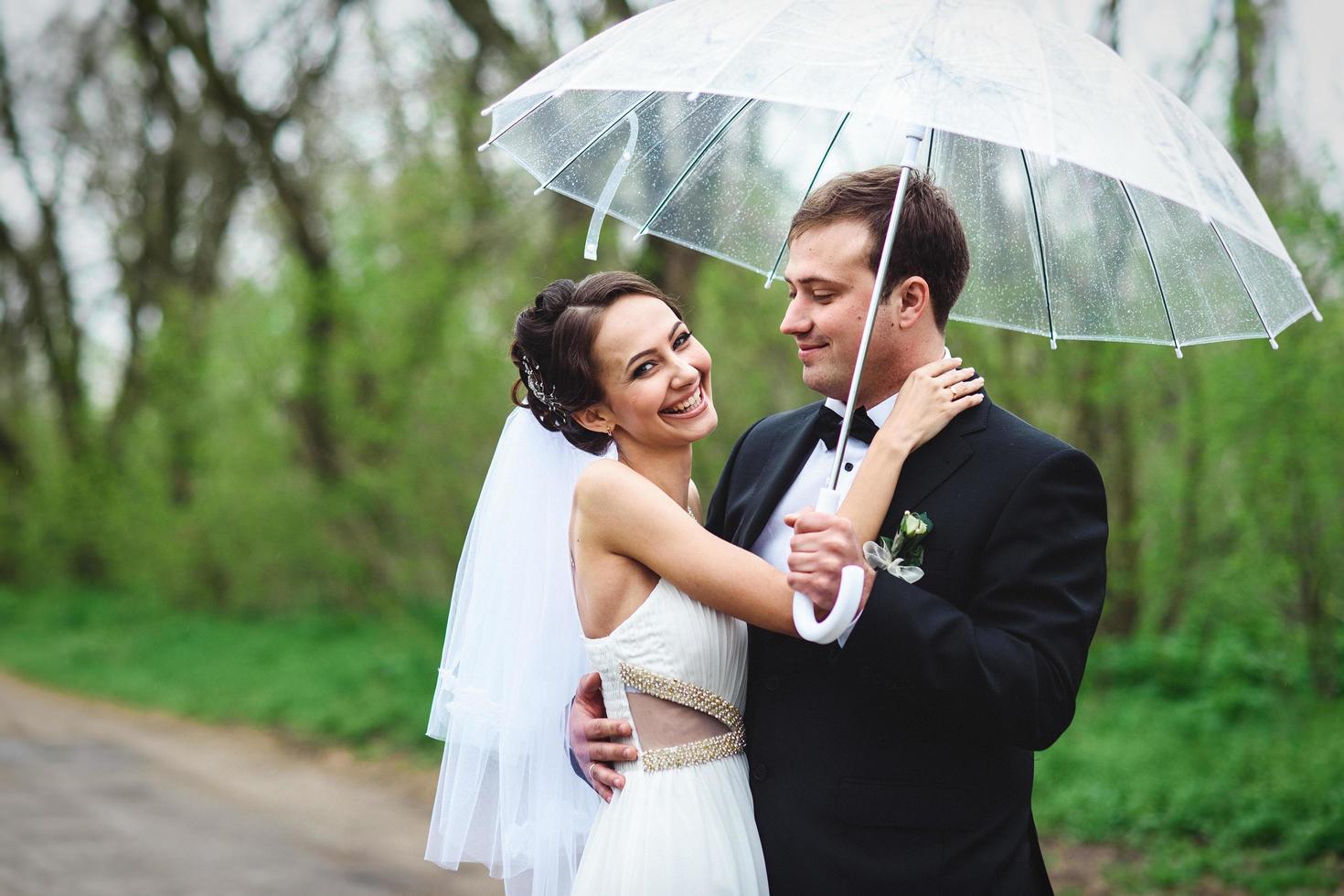 noiva e noivo em um dia chuvoso de casamento caminhando foto