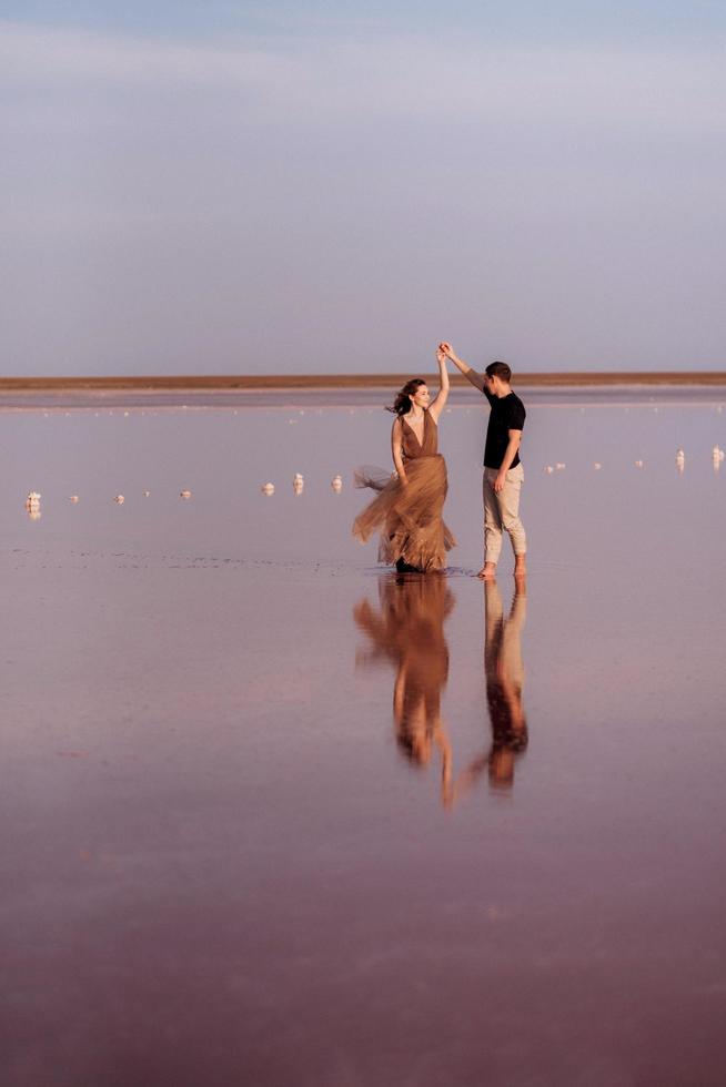 garota e um cara na margem de um lago salgado rosa foto