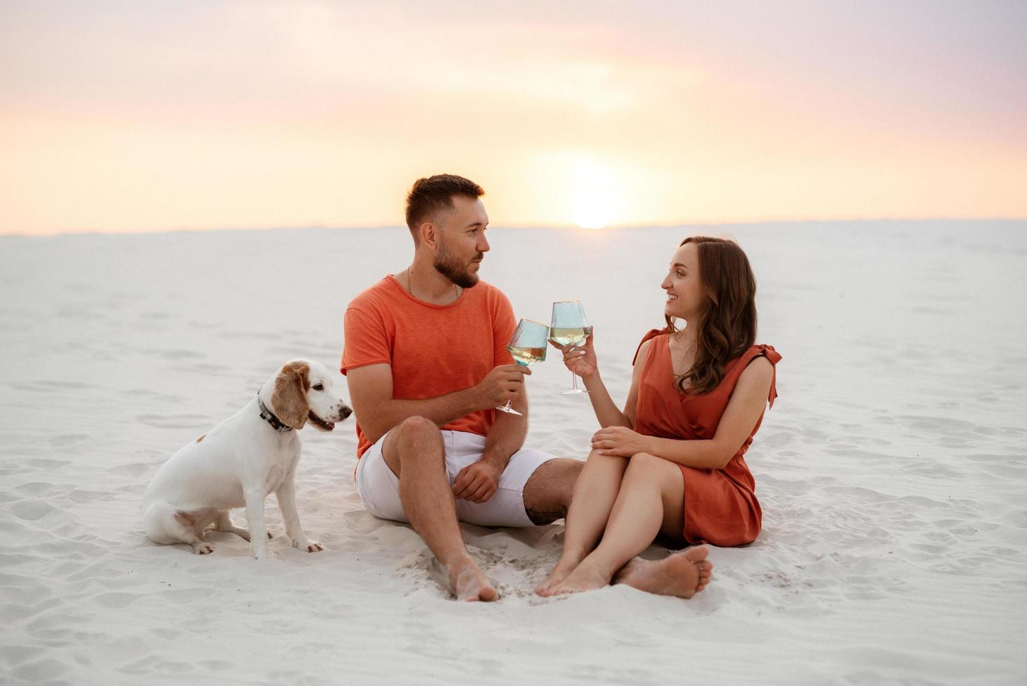 jovem casal em roupas laranja com cachorro foto