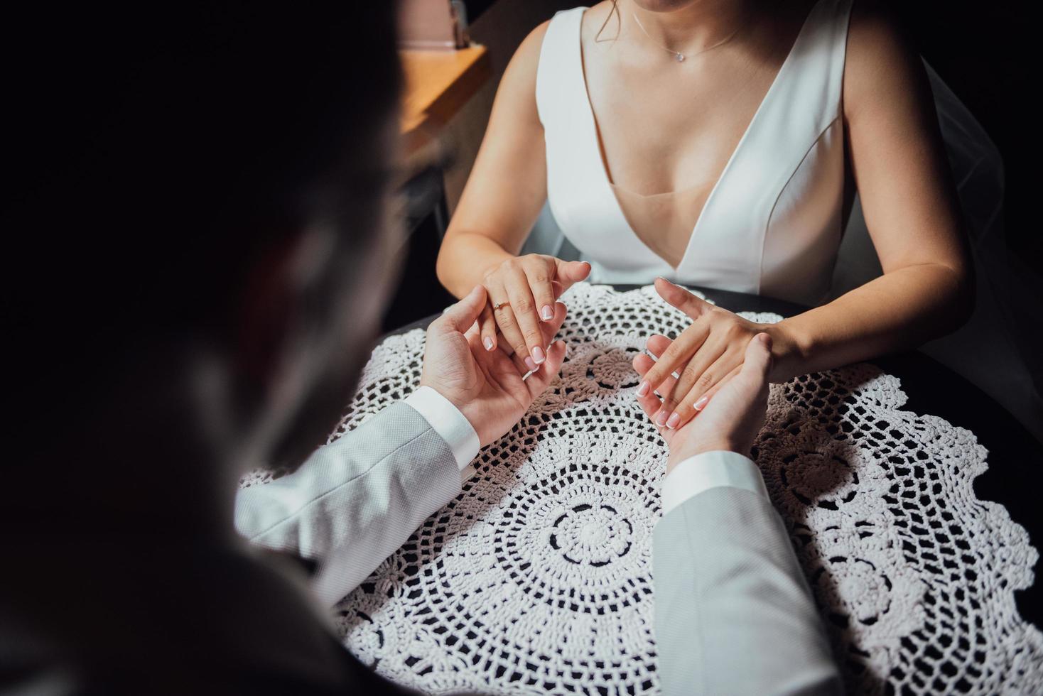 um cara de terno e uma garota de vestido estão sentados à mesa de mãos dadas foto