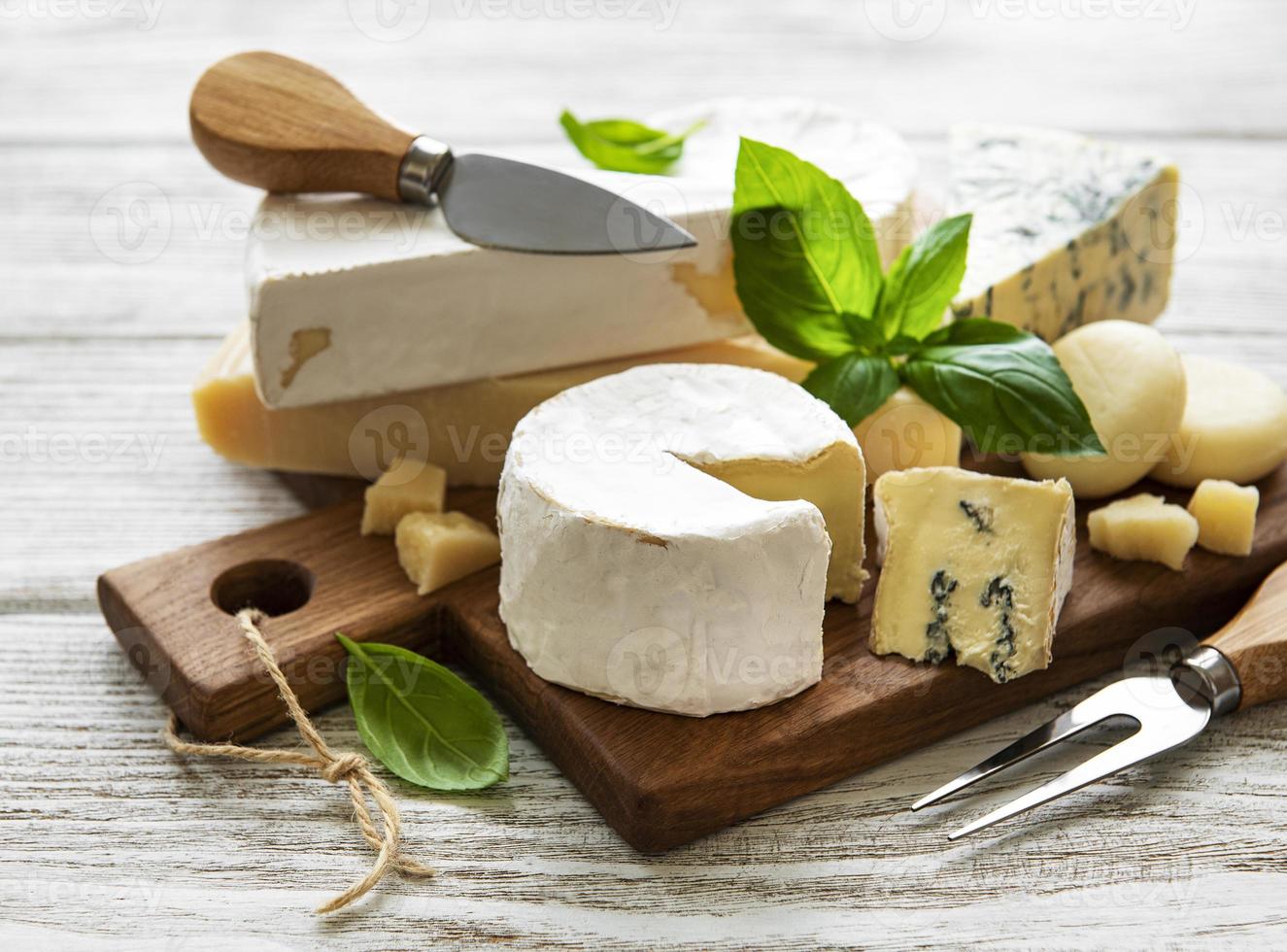 vários tipos de queijo em um fundo branco de madeira foto
