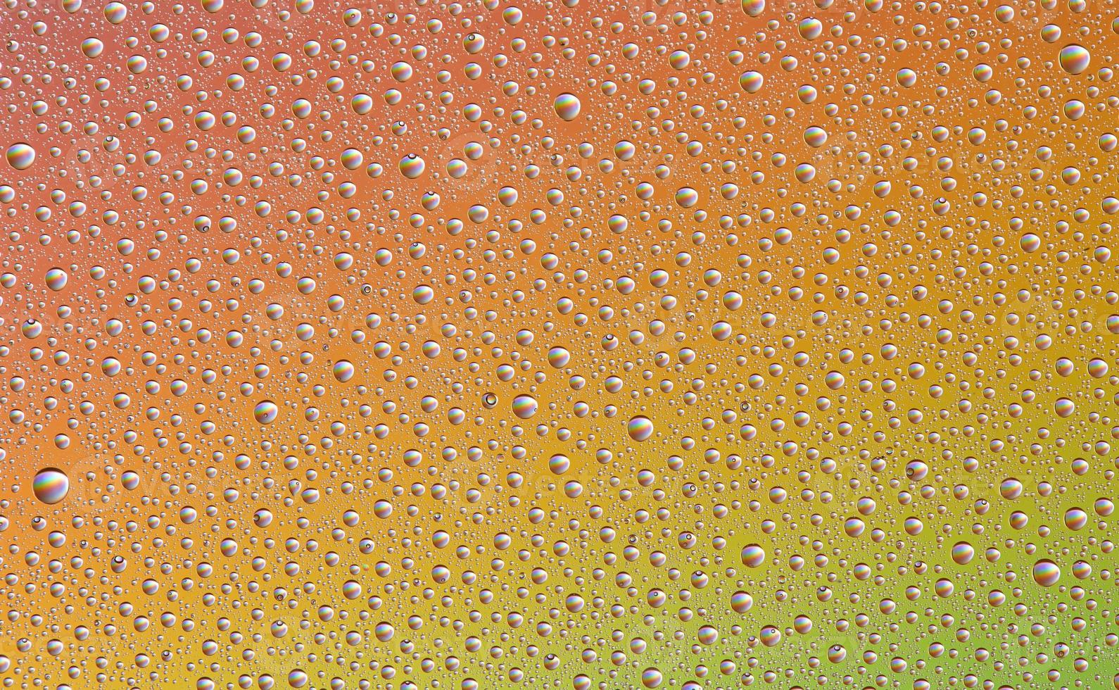 gotas em vidro de diferentes tamanhos e cores sobre um fundo colorido, textura foto