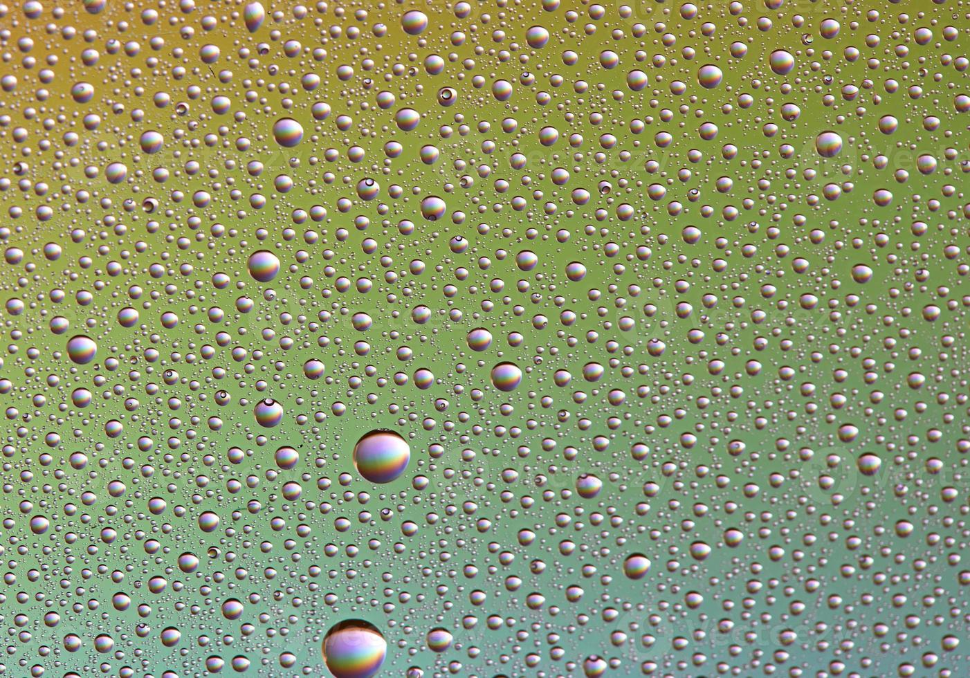 gotas em vidro de diferentes tamanhos e cores sobre um fundo colorido, textura foto