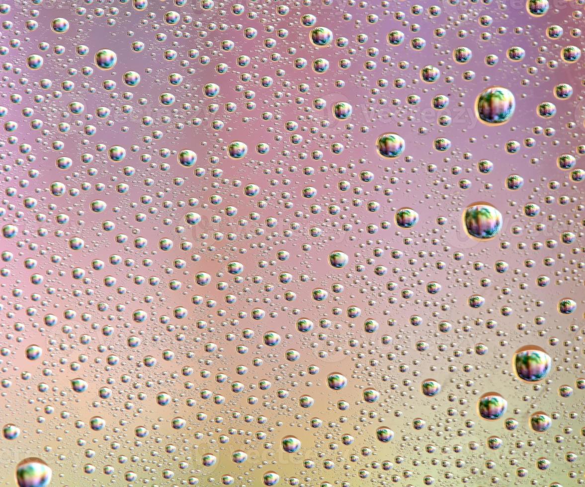 gotas em vidro de diferentes tamanhos e cores sobre um fundo colorido, textura foto