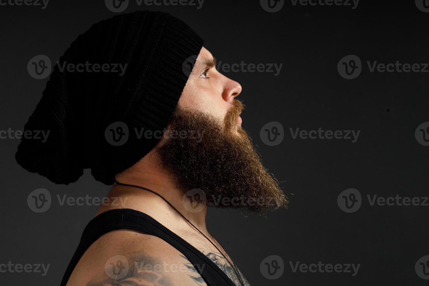 retrato de um homem barbudo bonito em uma jaqueta de couro e chapéu olhando para o lado foto