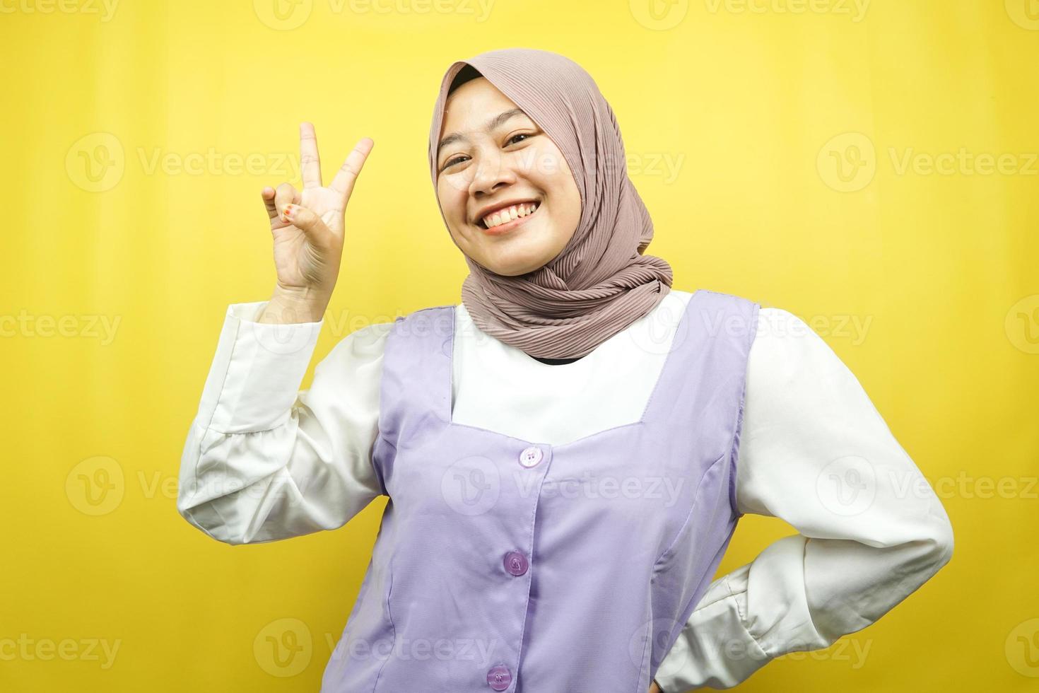 linda jovem asiática muçulmana fazendo beicinho com as mãos assinadas com V, ok, bom trabalho, acordo, vitória, olhando para a câmera isolada em fundo amarelo foto