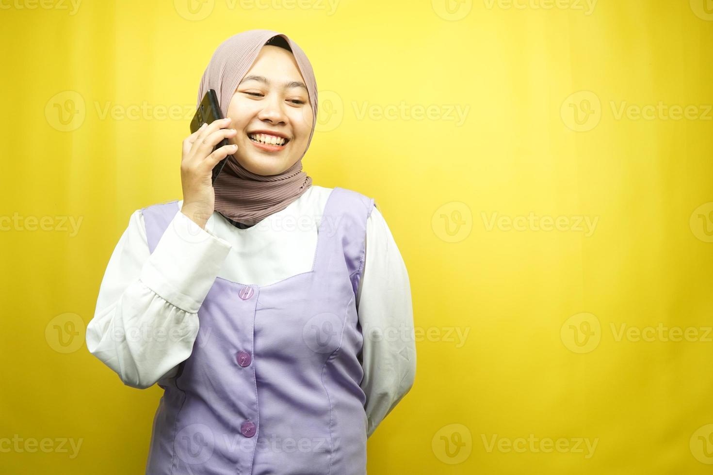 bela jovem asiática muçulmana sorrindo com confiança e alegria, ligando para alguém, de frente para o espaço vazio, isolado em um fundo amarelo, conceito de publicidade foto