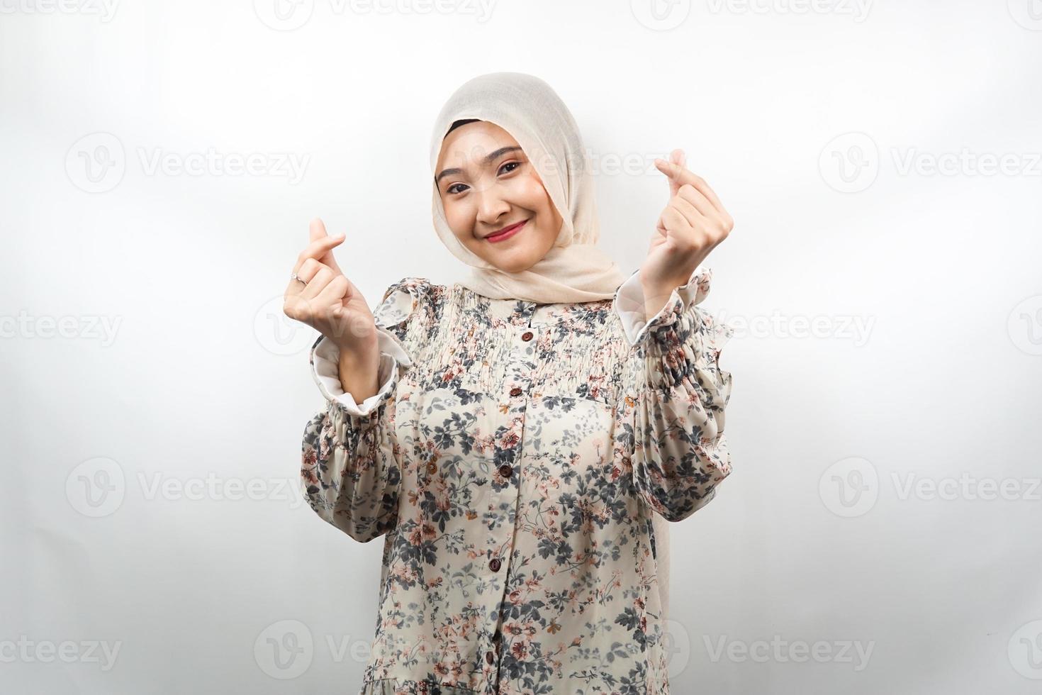 bela jovem asiática muçulmana sorrindo, com sinal de amor coreano, mão perto da câmera, isolado no fundo branco foto