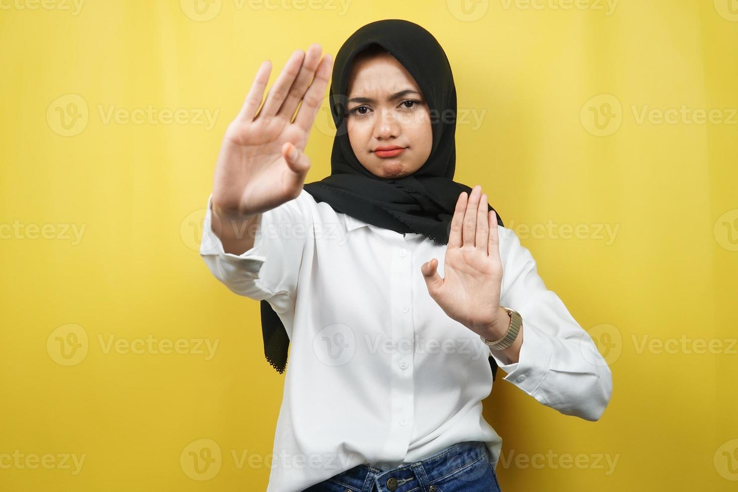 bela mulher asiática jovem muçulmana com a mão do sinal de parar, rejeitar a mão do sinal, mão do sinal de proibição, não se aproximar da mão, ficar longe da mão do sinal, não mover a mão do sinal, isolado no fundo amarelo foto