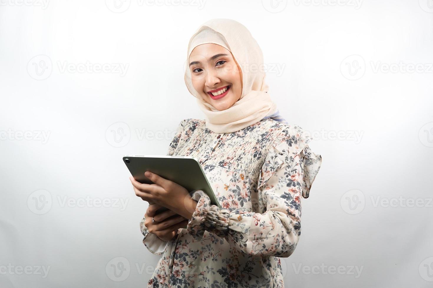 bela jovem asiática muçulmana sorrindo, animada e alegre segurando o tablet, isolado no fundo branco foto